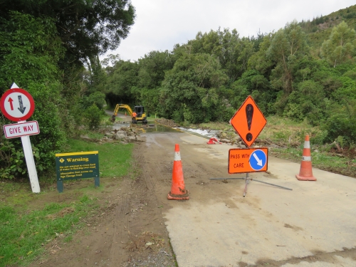 Digger removing debris from the flooded ford to clear the fish passage and allow vehicles to cross.